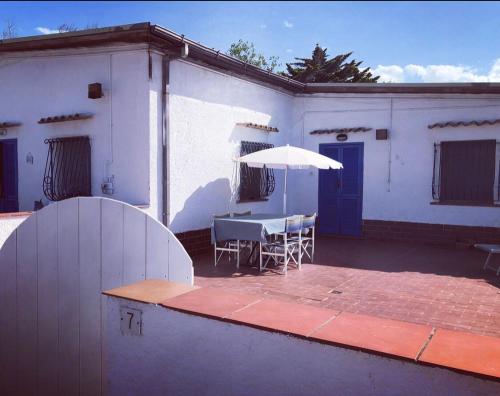a white house with a table and an umbrella at Appartamenti "LE CASETTE DI TERESA" in Ortona