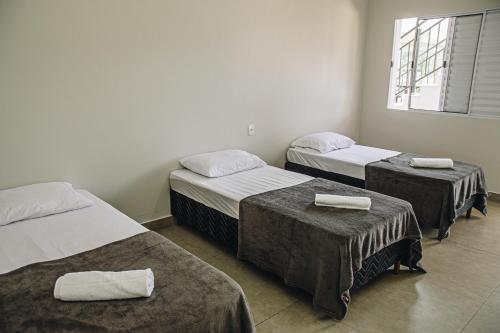 a room with three beds with towels on them at Pousada Casa Vista Bela São José da Barra Capitólio in São José da Barra