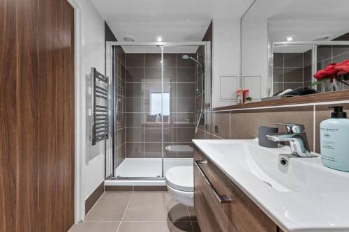 a bathroom with a sink and a toilet and a shower at New Apartment in Britannia point BP4 in London