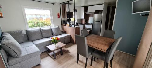 een woonkamer met een bank en een eettafel bij Mobil home neuf 693 à la réserve 8 personnes avec terrasse couverte in Gastes