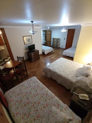 a room with three beds and a table and chairs at Hotel Paris Ltda. in Santiago