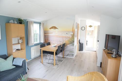 a living room with a table and a room with a view of the beach at Kustverhuur, Groede, Paarlhof 53 in Groede