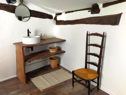 a bathroom with a sink and a mirror and a chair at L'Imprévu de Cotignac, Appart' et Duplex au cœur du village in Cotignac