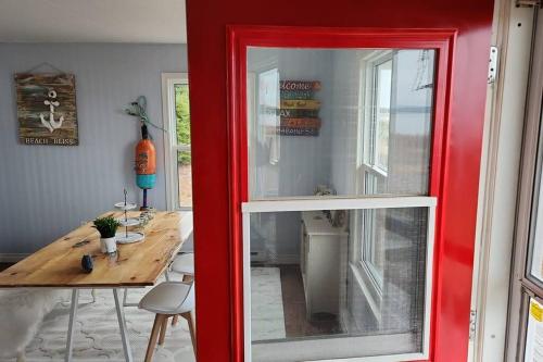 a red door leading into a dining room with a table at Beach Bliss, Great View in Guysborough