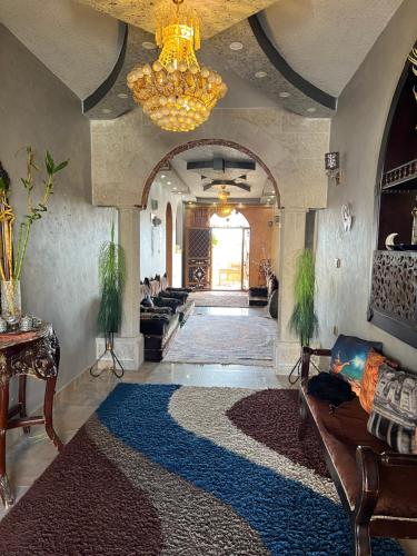 a living room with a chandelier and a large rug at Bedouin family home in Wadi Musa