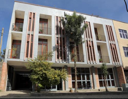 ein weißes Gebäude mit Fenstern und einem Baum davor in der Unterkunft Obelisk Hotel Axum in Aksum