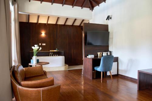 a living room with a chair a desk and a television at Seahorse Hotel & Spa in Negombo