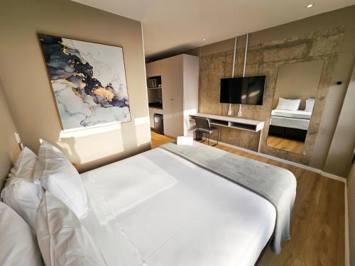 sypialnia z dużym białym łóżkiem i telewizorem w obiekcie Bewiki w mieście Florianópolis