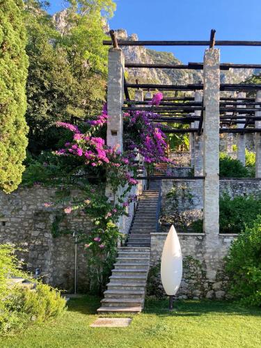a stone staircase with pink flowers and a white surfboard at 5 Terrazze Exlusive Apartments in Gargnano