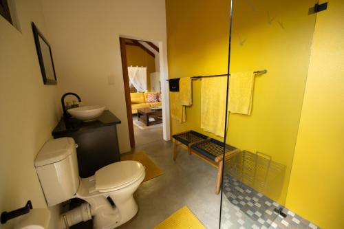 a bathroom with a toilet and a glass shower at Oriole Bush Cottage in Hoedspruit
