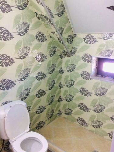a bathroom with a toilet and a tv on a wall at T&M Cottages in Bakuriani