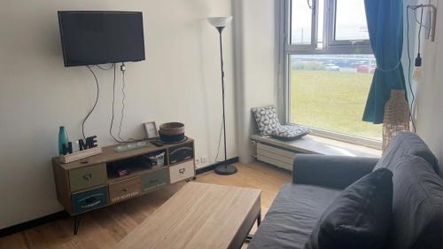 un salon avec un canapé, une table et une fenêtre dans l'établissement Front de mer avec vue sur le port, au Havre