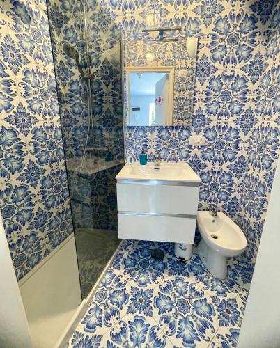 a blue and white bathroom with a sink and a mirror at La Cuchina in Capri