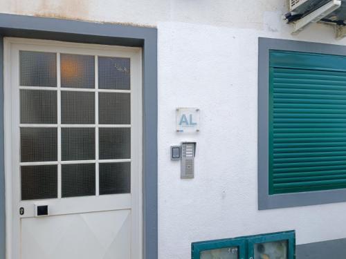 a building with a door and a green shutter at Apartamento Valados in Ponta Delgada