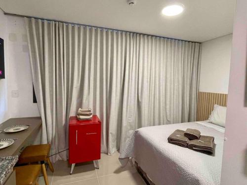 a bedroom with a bed with a red cabinet and a table at Studio bem localizado / Prox estação Trianon in São Paulo