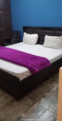 ein großes Bett mit einer lila Decke drauf in der Unterkunft Ak Residency-18 in Noida