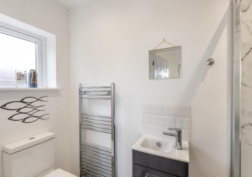 uma casa de banho branca com um lavatório e um espelho em Seashells em Georgeham