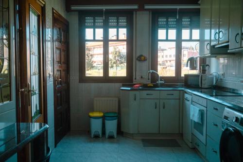a kitchen with white cabinets and a sink and windows at Chalet Bilbao-Aeropuerto in Sondika