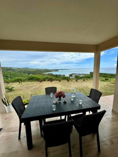 a black table with chairs and a view of a field at La Residence Emmaüs in Rodrigues Island