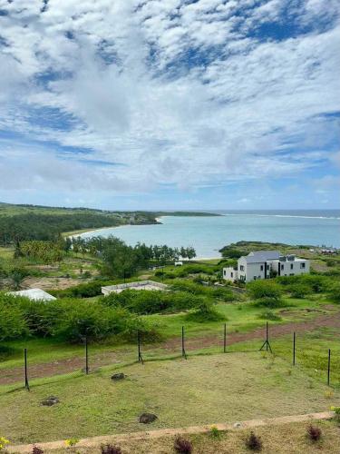 a field with a house and a body of water at La Residence Emmaüs in Rodrigues Island