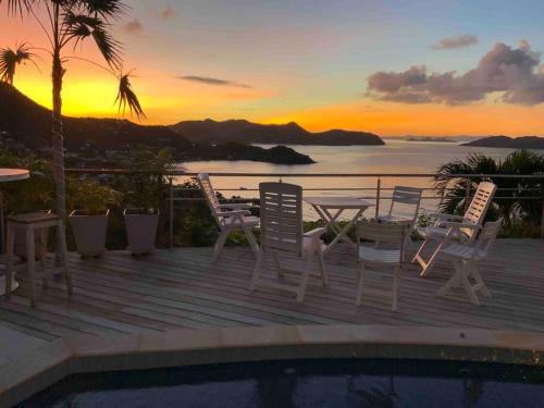 a deck with chairs and a table and a sunset at Maison des Brin - Lorient Camaruche in Saint Barthelemy