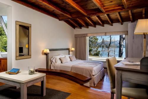 a bedroom with a bed and a table and a desk at Sol Arrayan Hotel & Spa in Villa La Angostura