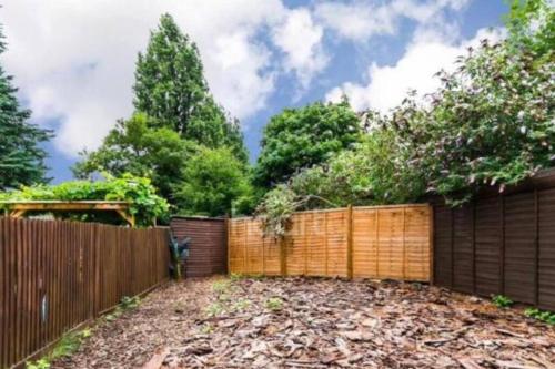 a backyard with a wooden fence and trees at 1 bedroom ground floor flat in Greenford