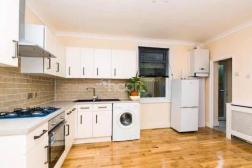 a kitchen with white cabinets and a washer and dryer at 1 bedroom ground floor flat in Greenford