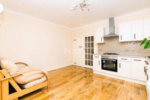 a kitchen with white cabinets and a wooden floor at 1 bedroom ground floor flat in Greenford