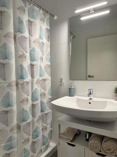 a bathroom with a sink and a shower curtain at APARTAMENTO ROMELIA bajo A in Tivenys