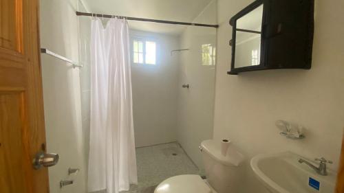 a white bathroom with a toilet and a sink at Dharma Casa Holistica, Vivero, Yoga y Retiros in Chame