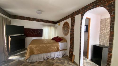 a bedroom with a bed and a brick wall at Dharma Casa Holistica, Vivero, Yoga y Retiros in Chame