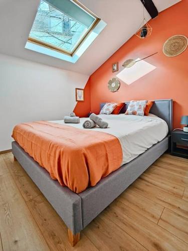 une chambre avec un grand lit avec un mur orange dans l'établissement Dolce Vita - Centre-ville - Paisible - Moderne, à Mulhouse