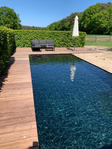 a swimming pool with an umbrella and a table and chairs at Vakantiehuis Eksel in Hechtel-Eksel
