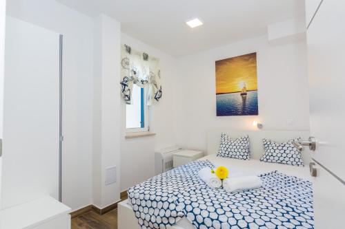 - une chambre blanche dotée d'un lit avec des draps bleus et blancs dans l'établissement Villa Miri Lily, à Privlaka