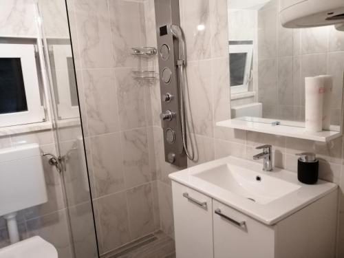 a white bathroom with a shower and a sink at Apartment Happy 2 in Pakoštane