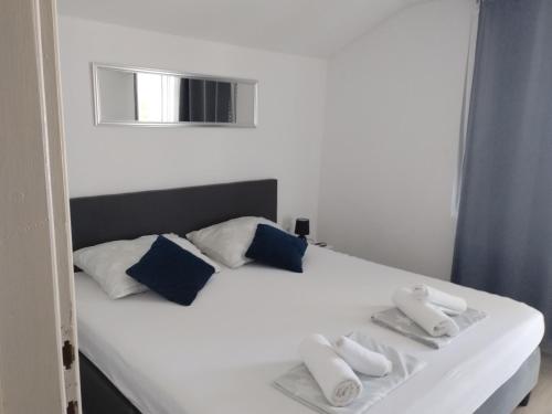 een slaapkamer met een wit bed met blauwe kussens bij Apartment Happy 2 in Pakoštane