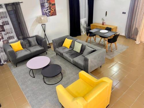 uma sala de estar com sofás, uma mesa e cadeiras em Luxe minontin em Cotonou