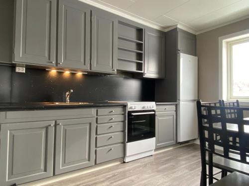 uma cozinha com armários brancos e um forno com placa de fogão em Sommerstad em Kongsberg