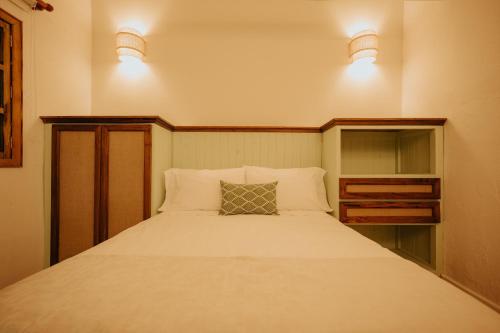 a bedroom with a large white bed with two lights at Hotel La Corada in Villa de Leyva