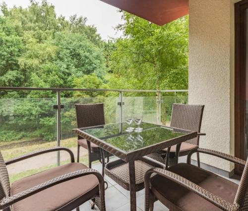 patio ze szklanym stołem i krzesłami na balkonie w obiekcie Seaside Forest - Apartment Polanki w Kołobrzegu