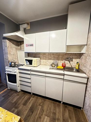 a kitchen with white cabinets and a sink and a stove at 4-км в центрі міста in Rivne