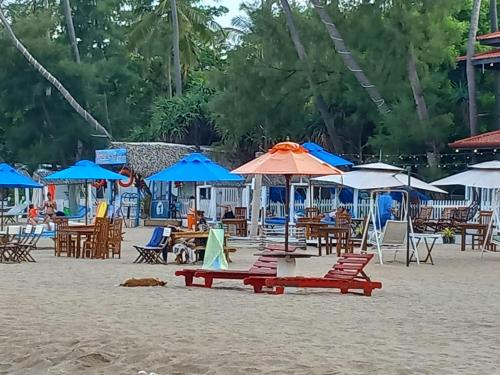 a beach with tables and chairs and umbrellas at So-J Beach Villa in Trincomalee