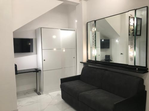 a living room with a black couch and a mirror at Studio Apartment Santa Caterina in Bologna
