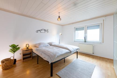 a white bedroom with a bed and a window at Pitlane-Apartment in Herresbach
