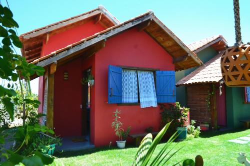 a red house with blue shutters on it at Chalés Cabocla da Lua in Caraíva