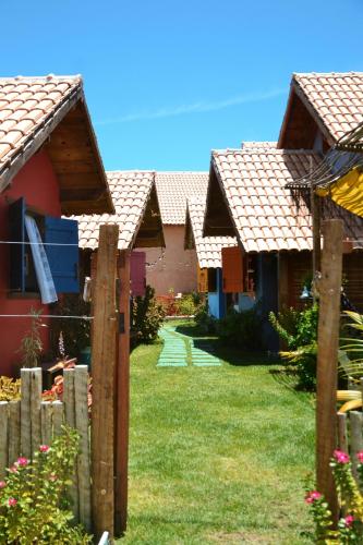 a row of houses in a yard with grass at Chalés Cabocla da Lua in Caraíva