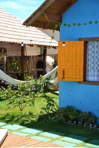 a blue house with a hammock in the yard at Chalés Cabocla da Lua in Caraíva