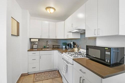 a white kitchen with white cabinets and a microwave at Sleek 1-Bedroom Apt in Chicago - East Park Tower 0610 rep in Chicago