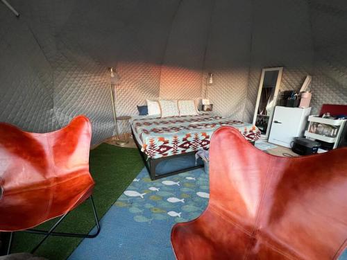 a bedroom with a bed and two chairs in a tent at Sunset Dome - Outdoor Shower/Composting Toilet in Valley Center